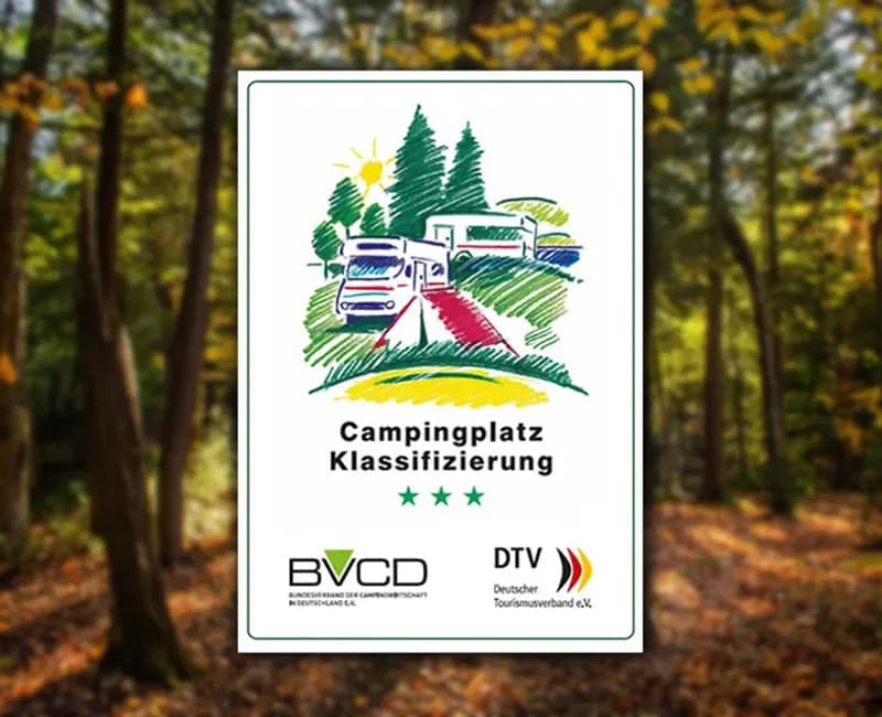 Schild „Campingplatz Klassifizierung" mit drei Sternen und den Logos von BVCD und Deutschem Tourismusverband, dahinter ein Wald